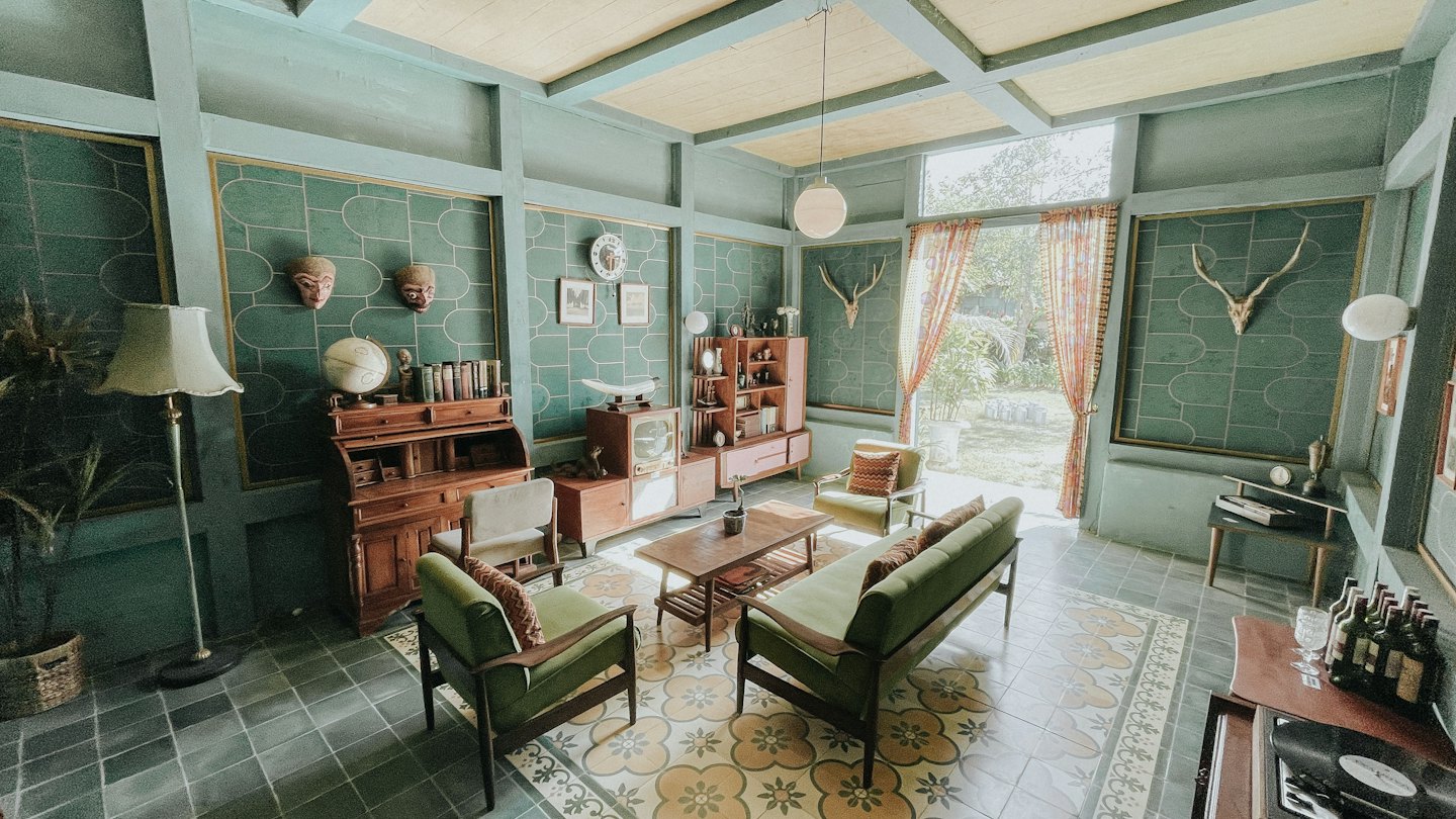 Gemütliches Wohnzimmer im Vintage-Stil mit grünen Sofas und türkisfarbenen geometrischen Wänden.